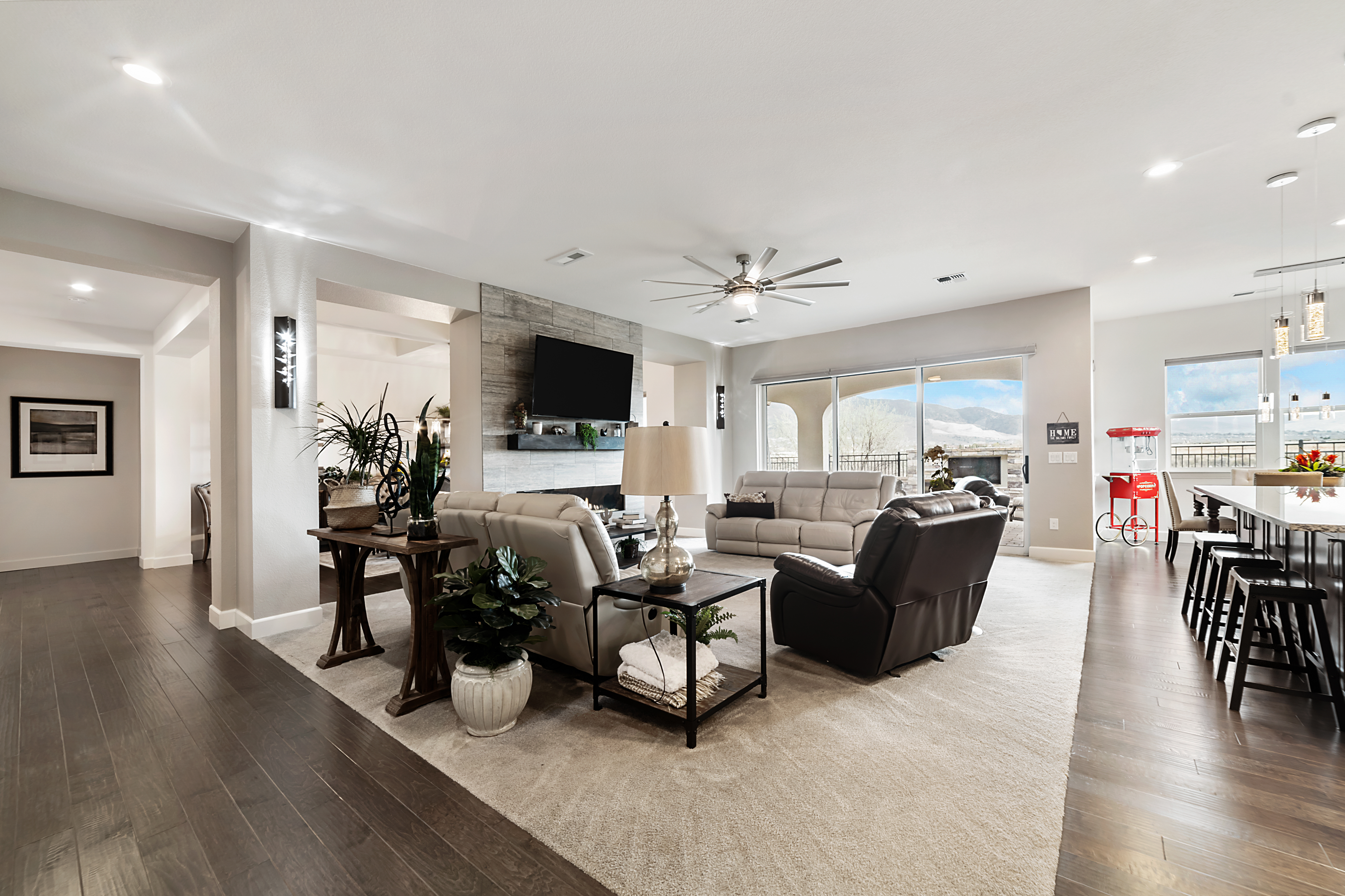 Open and bright living room with hanging television, couches, and tables. 