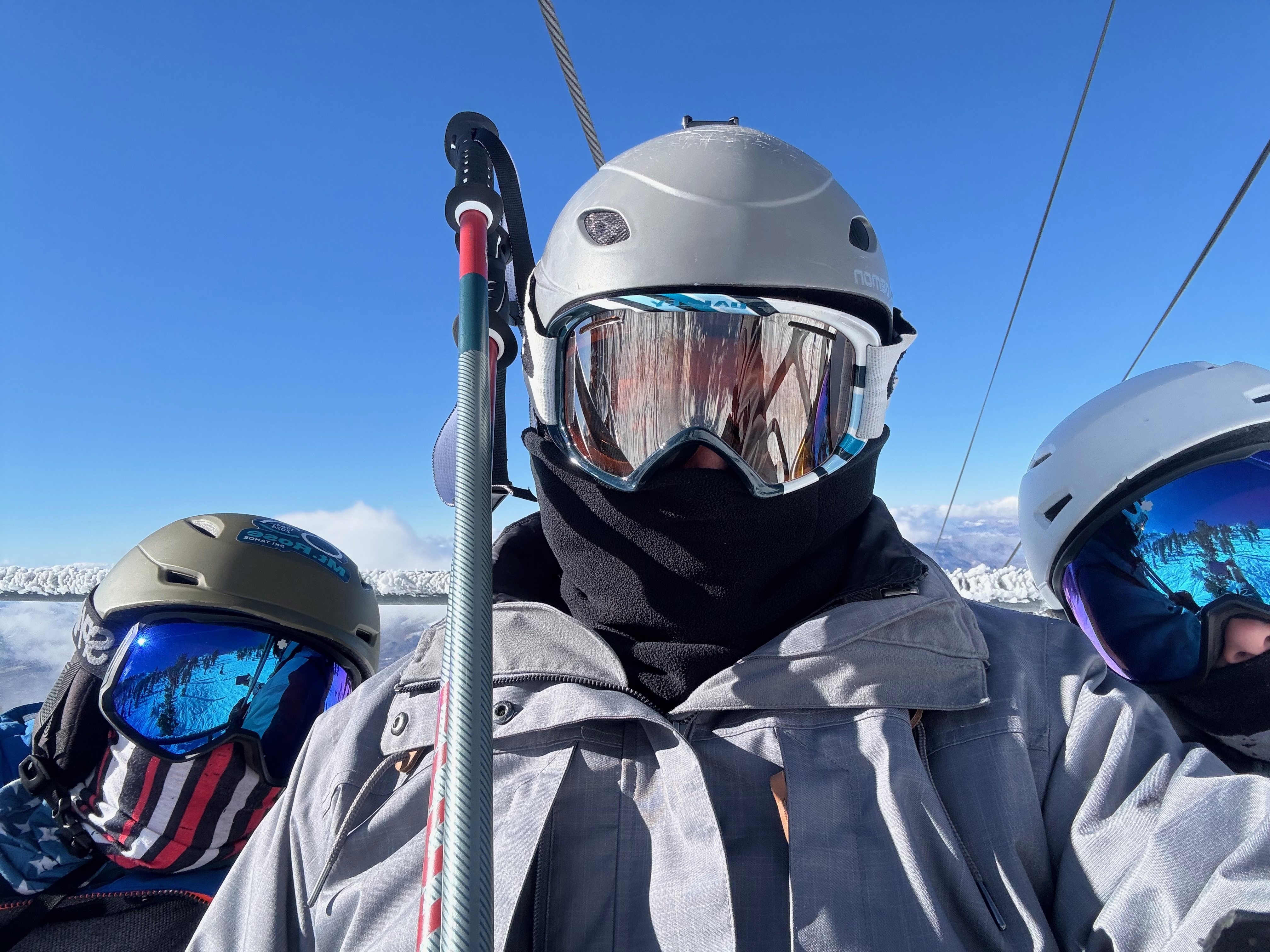 Ken Angst and his sons with skiing googles on sitting on a ski lift. 