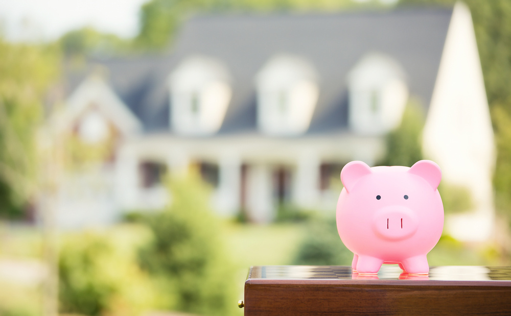 Piggy bank in foreground of blurry two story home