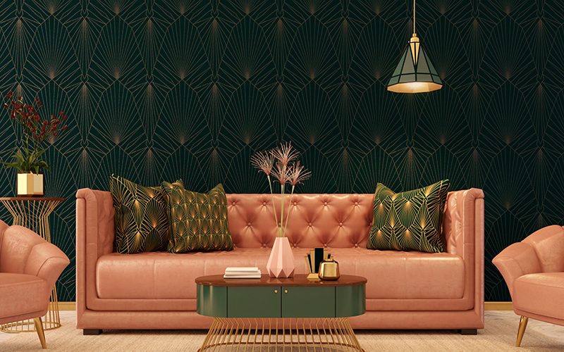 Salmon colored couch with green pillows in front of a dark forest green wallpapered wall highlighted with gold accents in the wallpaper.