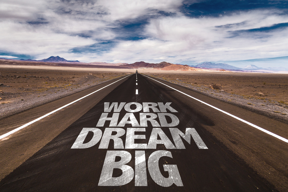 Text Work Hard Dream Big in white on roadway