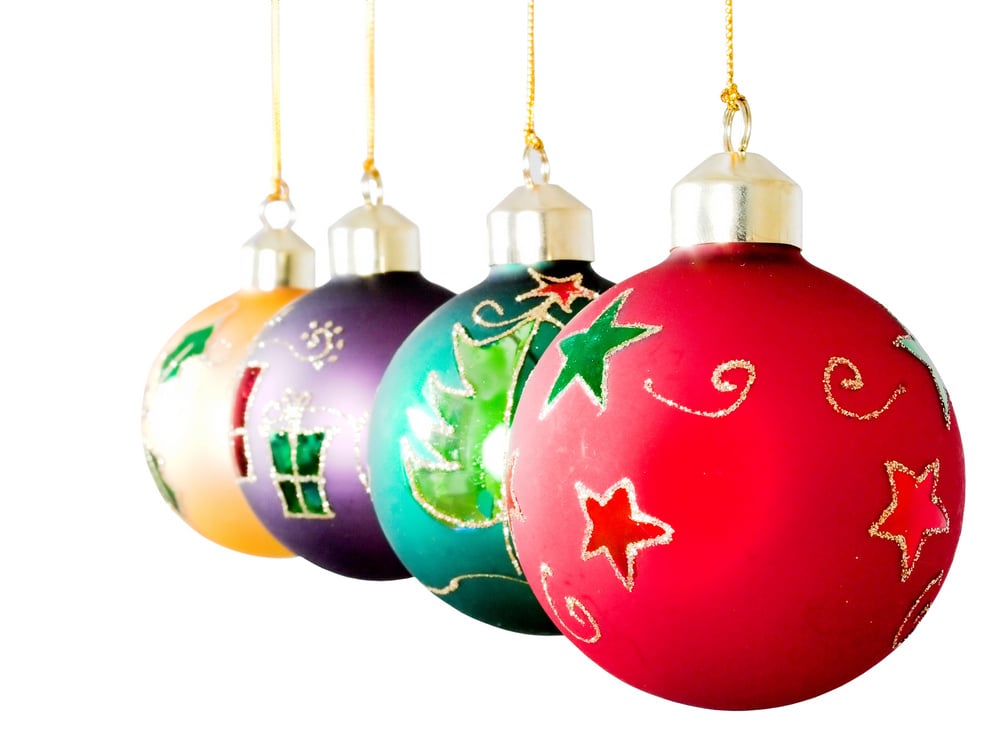 Colorful Christmas ball ornaments hanging in a row on white background.